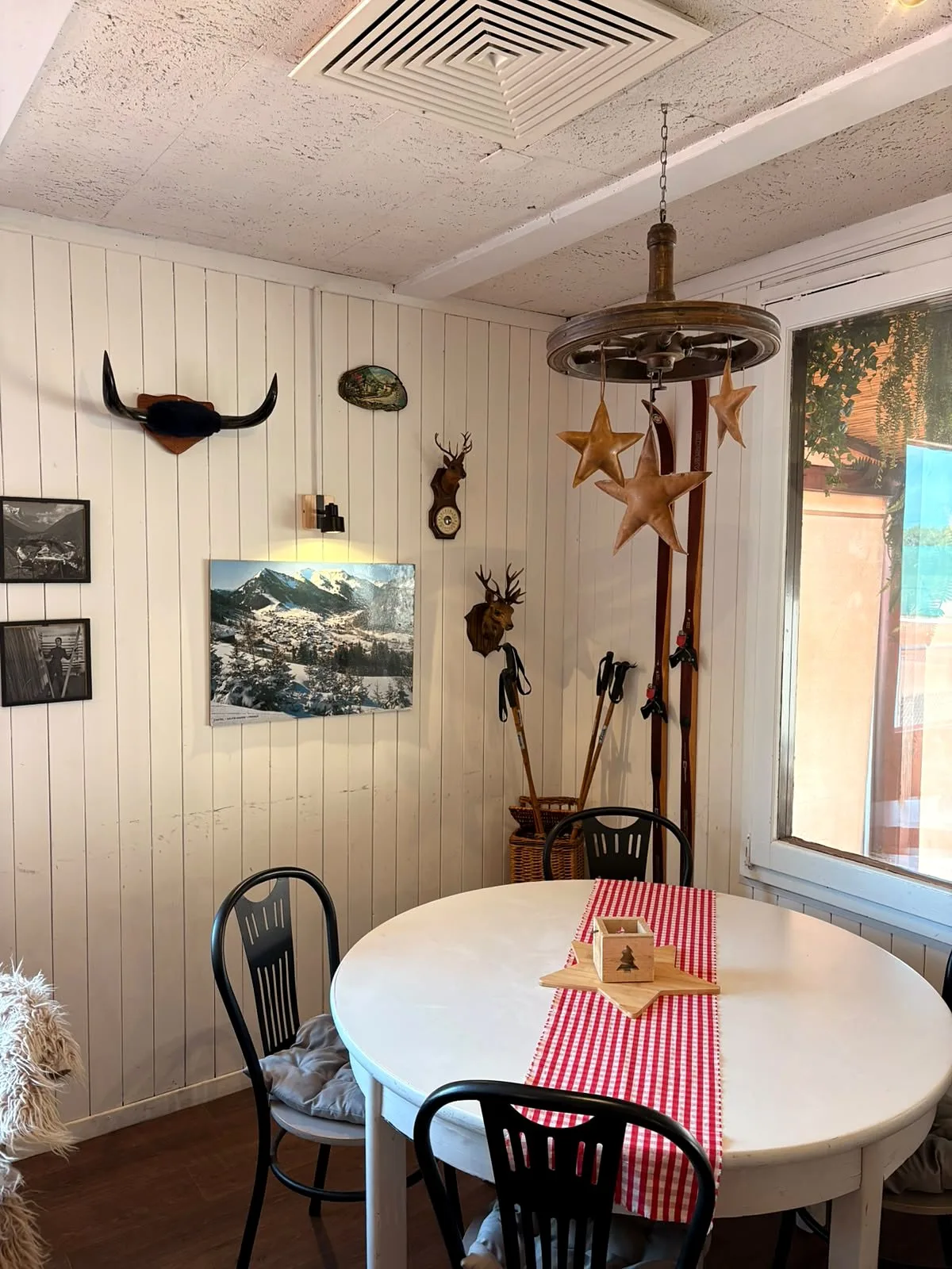 Coin de la salle avec une table ronde, des skis anciens, des trophées et des étoiles en bois